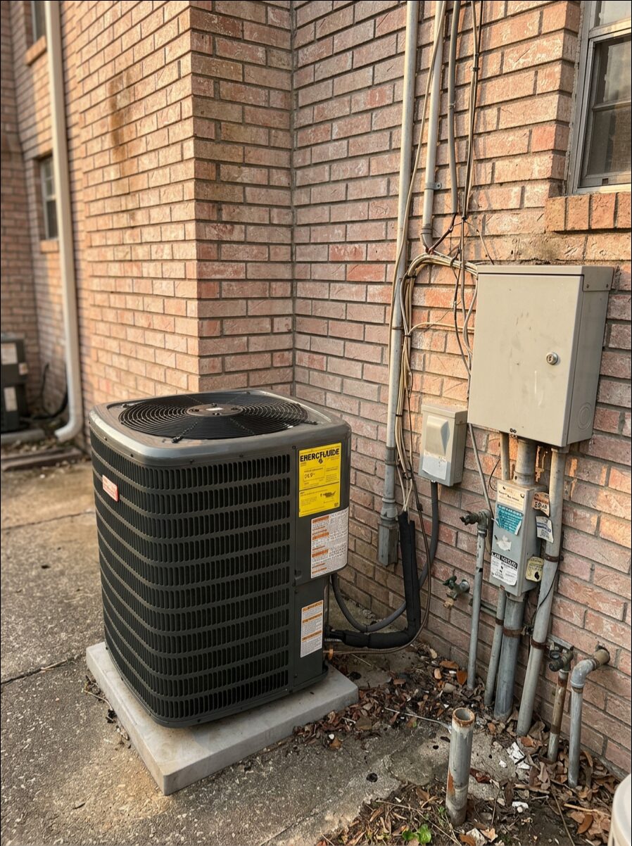 Central air conditioning condenser installed beside a brick home